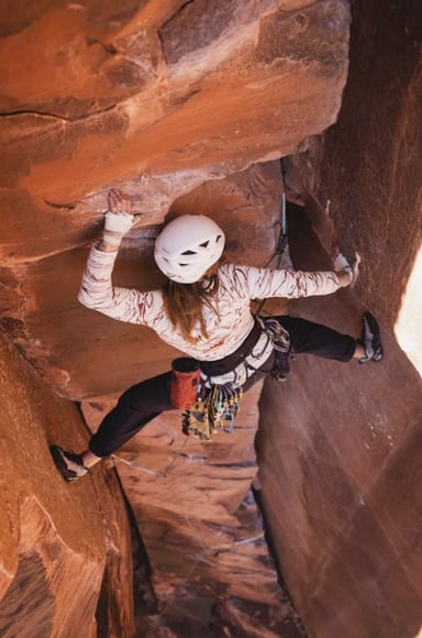 A climber in a helmet bridging up a sandstone chimney
