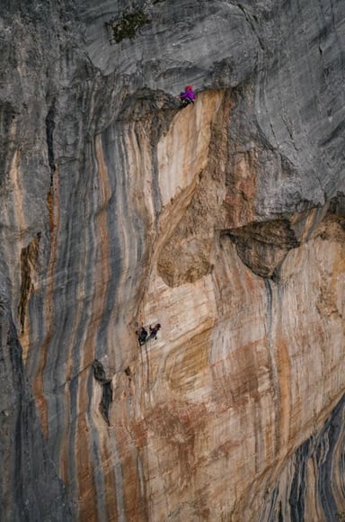 A climber on a huge orange limestone overhang